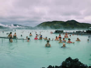 人群在冰島享受地熱溫泉，水蒸氣從水中升起。
