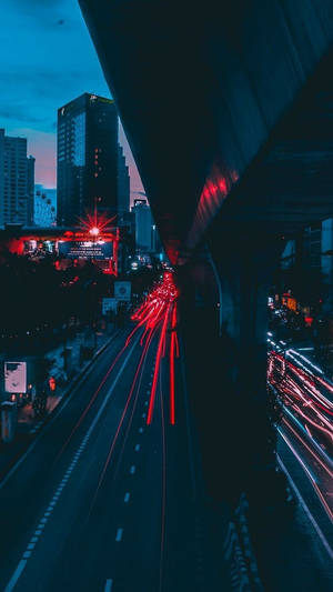 黃昏時分的城市高速公路，天橋下紅色和白色車燈的條紋。