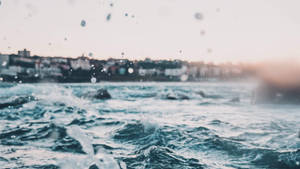 暮色中，海浪在沿海小鎮附近拍打，可見雨滴。