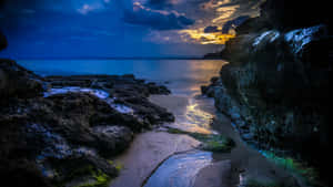 黃昏海灘，金色夕陽在黑暗岩石之間的平靜水面上反射。