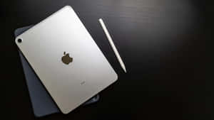 銀色iPad和白色Apple Pencil在深色木質桌面上。
