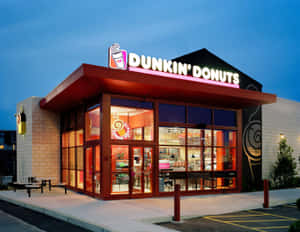 黃昏時照亮的 Dunkin' Donuts 店舖，內部可見座位和標誌。 — 咖啡 壁紙