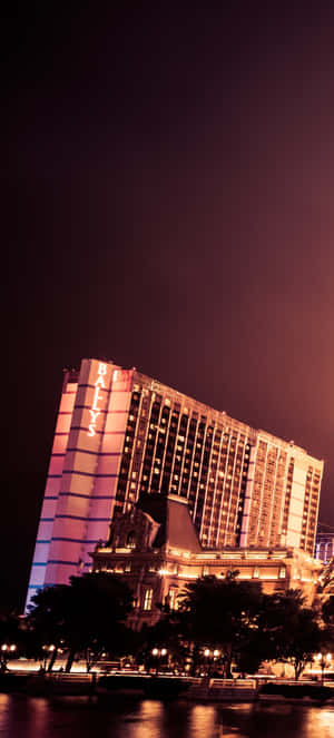 夜晚燈火通明的酒店建築，水面倒映著燈光。