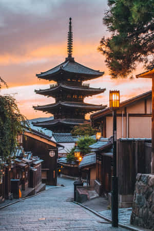 日落時分的傳統日本寺廟塔樓，石頭街道旁閃耀的燈籠。