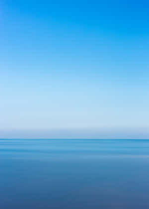平靜的藍色海水在地平線與晴朗的天空相遇。 — 藍天 壁紙