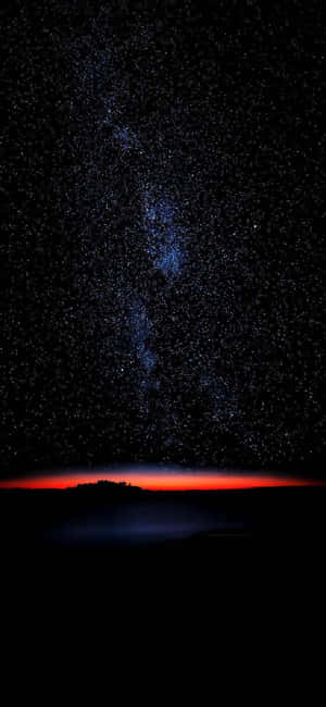 星空夜空，暗色陸地剪影上方有紅色地平線。