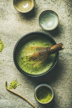 黑色碗中的抹茶，配以竹筅和陶瓷杯，置於石面上。 — 小米Pad 7 Ultra 壁紙