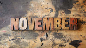 在骯髒的工作枱上拼出November的復古木製活字塊。