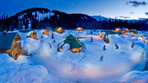 積雪的小屋亮著溫暖的燈光，坐落在暮色中的山林裡。