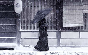 穿著黑色和服撐傘的人走在積雪的日本街道上。