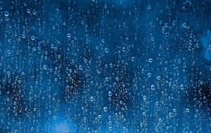雨滴在藍色背景的玻璃窗上滑落。