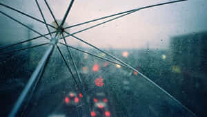 雨中城市駕駛時從透明傘下觀看，帶有模糊燈光。
