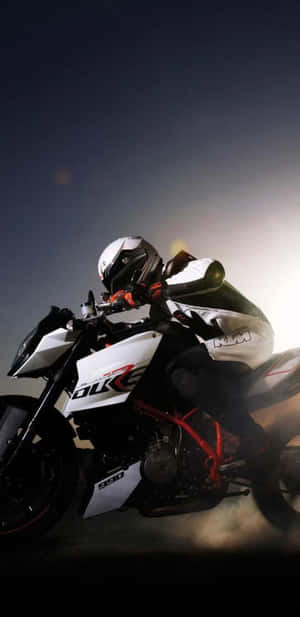 電單車手在夜間以戲劇性燈光在KTM Duke 990上傾斜入彎。 — Galaxy S10 壁紙