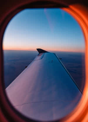 從乘客窗戶看到的飛機機翼，夕陽西下。 — 天空景觀 壁紙
