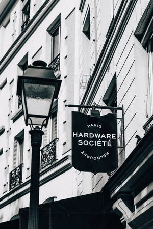 黑白街景，歐洲建築上有復古燈和Hardware Société標誌。