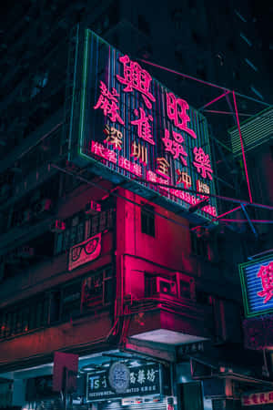 霓虹燈在夜間以粉紅色和綠色色調照亮密集的城市建築。