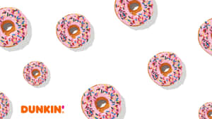 白色背景上帶有Dunkin'標誌的粉紅色糖霜甜甜圈配彩色糖粒。