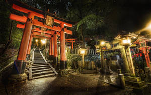 日本神社石階梯旁夜晚發光的紅色鳥居。