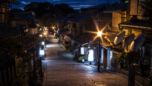 一條狹窄的石頭街道，兩旁是傳統的日本建築，夜晚被溫暖的燈籠照亮。