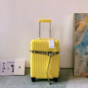黃色RIMOWA行李箱配OFF-WHITE帶子，現代房間內有藝術品和品牌盒子。