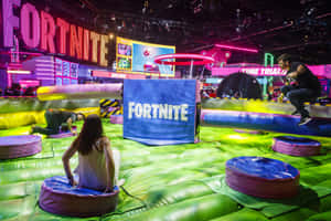 人們在遊戲活動中於Fortnite主題的充氣障礙賽道上玩耍。 — MacBook Air M2 壁紙