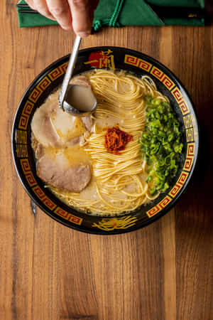 手從冒煙的拉麵碗中舀起湯匙，碗裡有豬肉和蔥花。 — 美食 壁紙