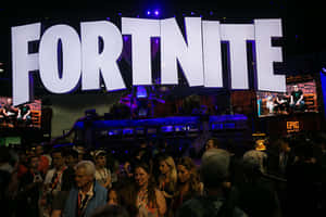 粉絲在大型照明標誌下參加 Fortnite 遊戲活動。 — MacBook Pro M4 壁紙