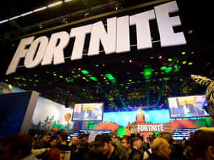 在明亮燈光和大螢幕下的Fortnite遊戲活動中的人群。 — 遊戲 壁紙