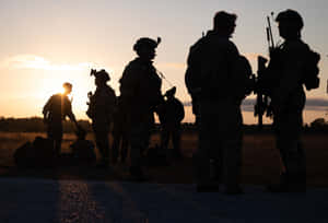 士兵剪影映襯著金色夕陽，在開闊的田野中。 — 日落 壁紙