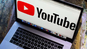 手提電腦在木質表面上顯示 YouTube 標誌 — YouTube 壁紙