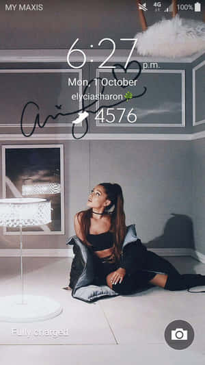 Ariana Grande 坐在現代房間的地板上，有白色燈和灰色牆壁。