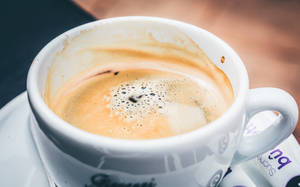 白色杯中半杯濃縮咖啡，附近有糖包。