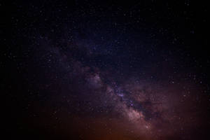 銀河系在黑暗的夜空中閃耀著紫色和粉紅色的星星。