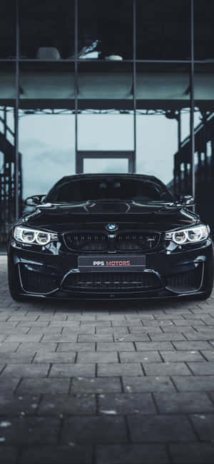 黑色BMW M4跑車停放在現代玻璃牆車庫的磚地上。