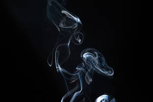 優雅的藍色煙霧漩渦在純黑色背景上昇起。