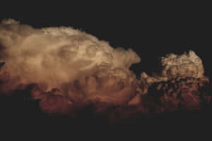 在漆黑的夜空中，戲劇性的雲朵被琥珀色和紅色照亮。