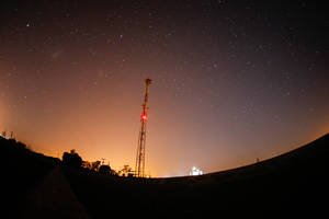 高塔在繁星夜空下，地平線上有橙色光芒