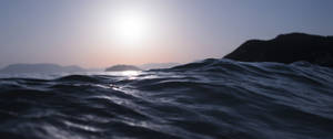 夕陽下的海浪與遠方山丘 — 銀河系 壁紙
