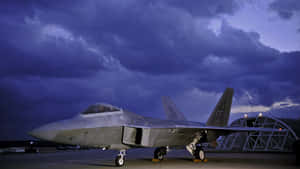 灰色戰鬥機停在停機坪上，紫色暮色天空有雲。