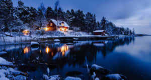 夜間水邊的雪地小屋，溫暖燈光倒映在平靜水面
