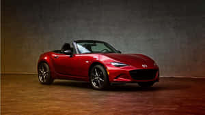 攝影棚內有紋理牆壁和溫暖燈光的紅色Mazda Miata開篷車。
