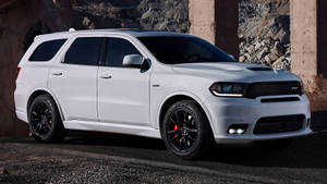 白色Dodge Durango SRT SUV停泊在混凝土柱下，靠近岩石地形。 — 汽車 壁紙