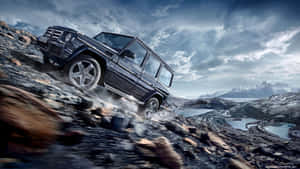 黑色 Mercedes G-Class 在岩石地形上行駛，背後有雪山和湖泊。