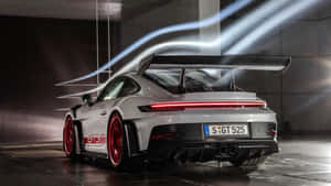 銀色保時捷911 GT3 RS，配備紅色輪圈和發光尾燈，在現代車庫中帶有光軌。