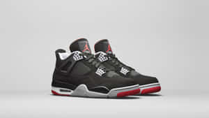 灰色背景上的黑色Jordan 4運動鞋，帶有紅色鞋底和白色點綴。