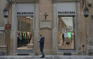 戴口罩的男子在城市街道上走過 Balenciaga 時裝店。