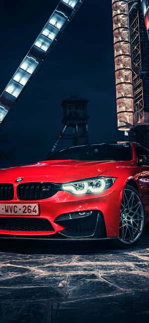 夜晚在發光的霓虹招牌下，停在石頭街道上的紅色BMW M4。 — Huawei nova 16z 壁紙