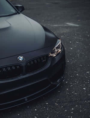 啞光黑色BMW M2跑車停在瀝青路上，帶有發光的頭燈。