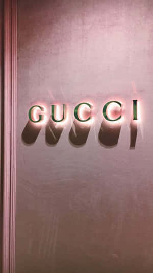 Gucci 標誌字母在帶有紋理的粉紅色牆壁上發光。