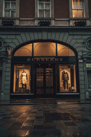 Burberry 店舖正面，穿著風衣的人體模型在黃昏時在濕漉漉的鵝卵石上發光。